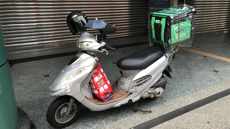 停在騎樓鐵捲門前的機車，後座綁著外送保溫箱